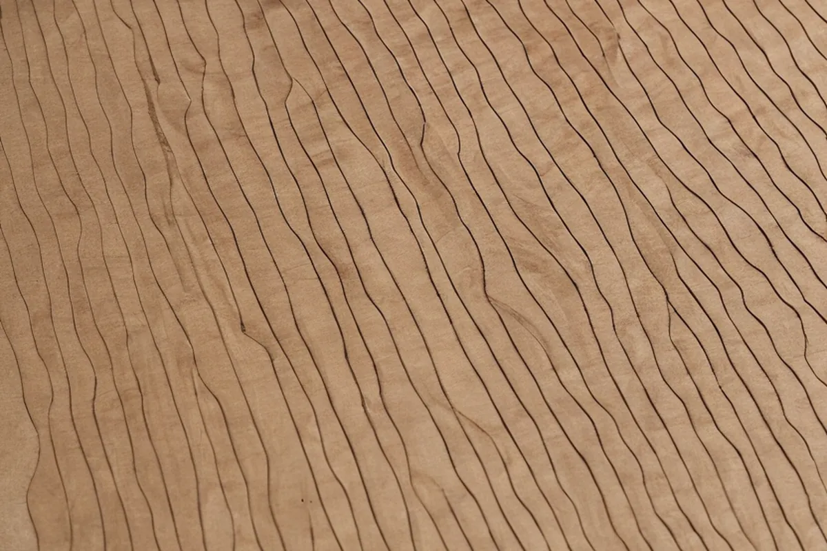 A laser cutting head working over a sheet on a honeycomb bed